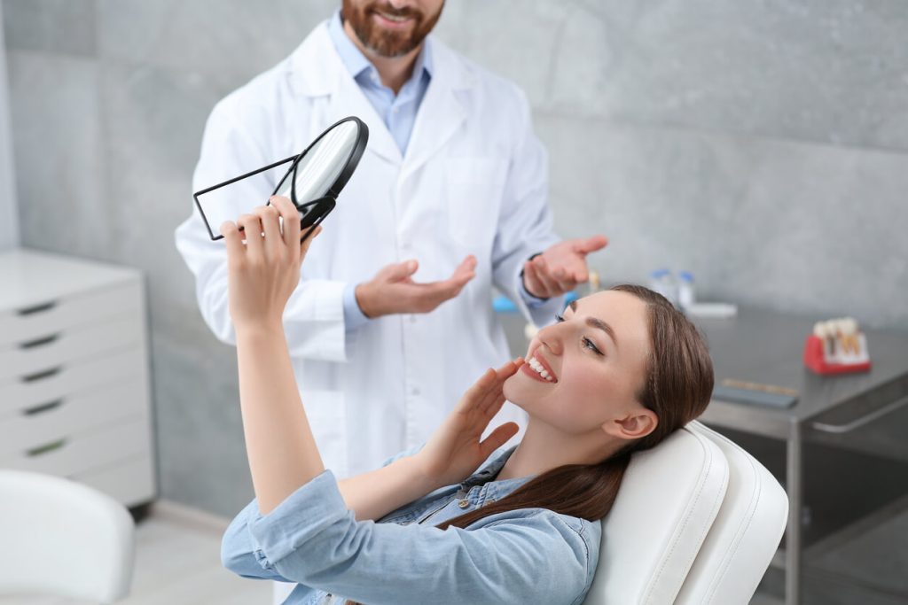 Woman looking at her new dental crowns in mirror.